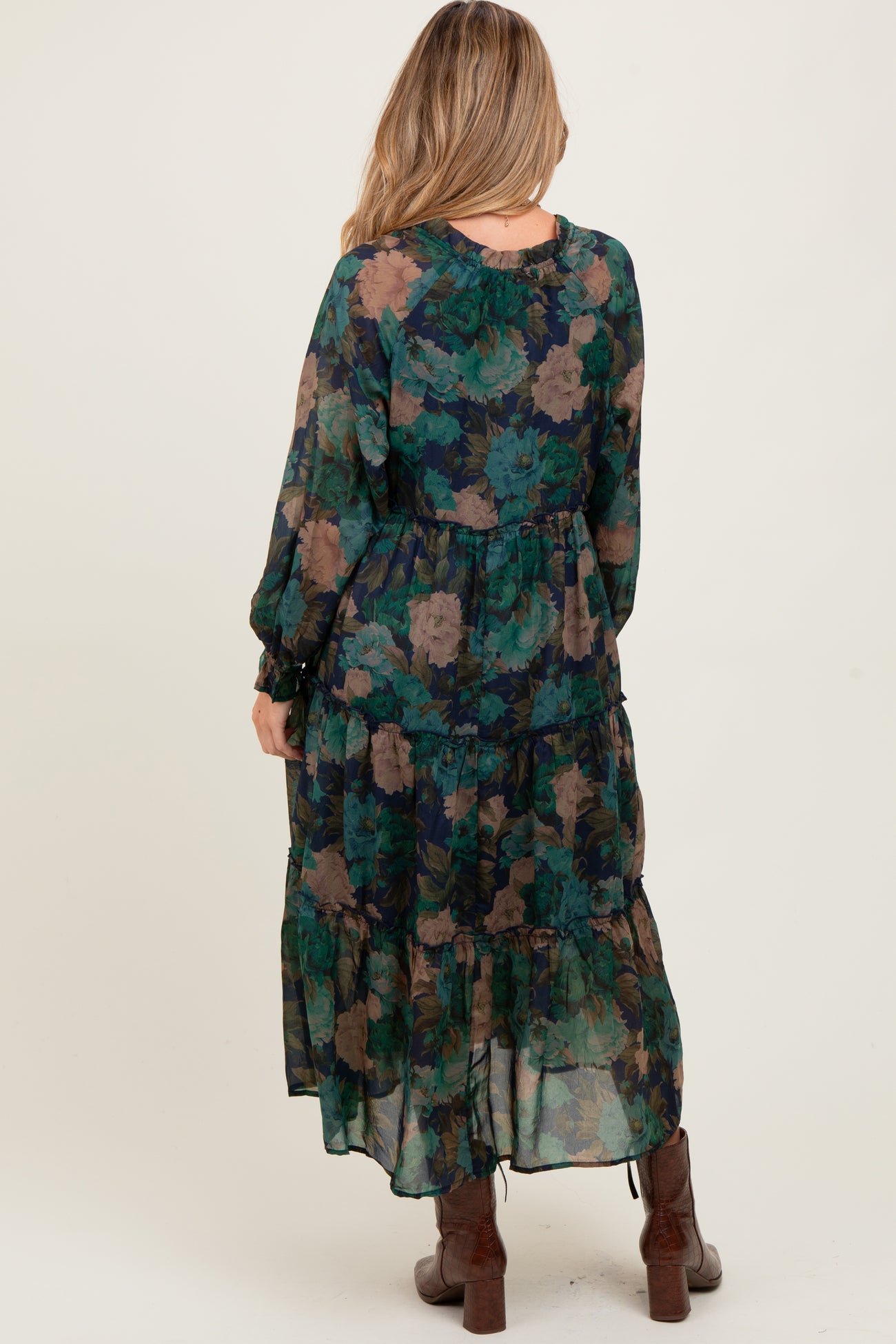 woman wearing a flowy green floral maternity maxi dress with long sleeves and ruffle details, showcasing a baby bump