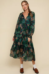 woman wearing a floral print maternity maxi dress with long sleeves and tiered ruffles, showcasing a baby bump