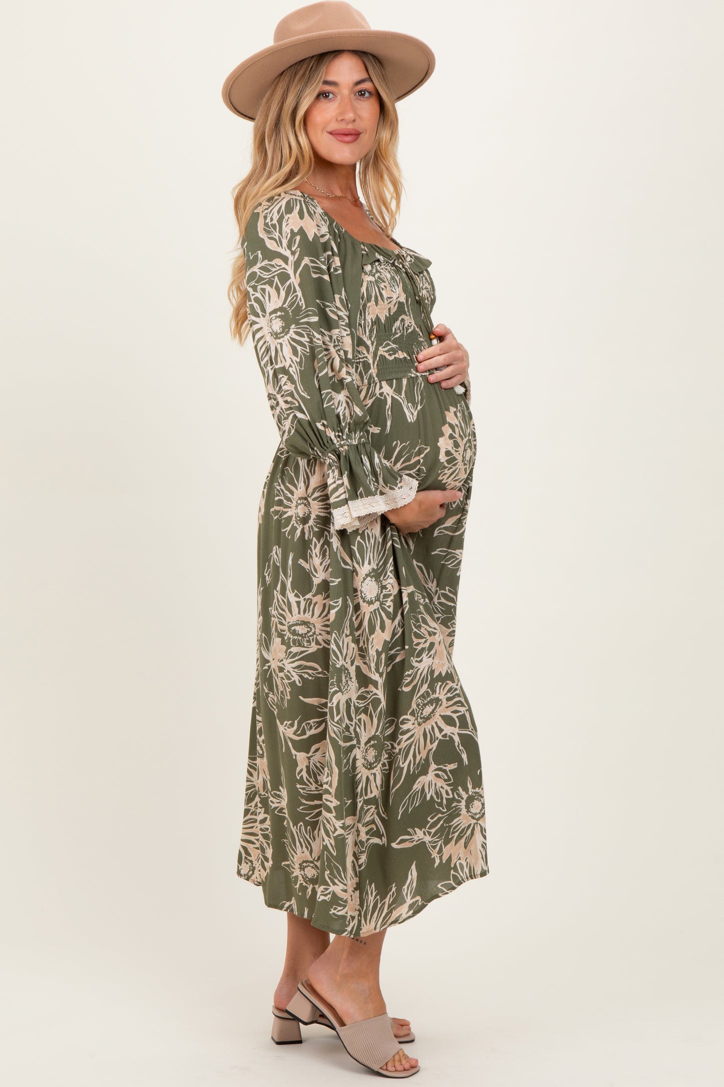 woman wearing a green floral maternity dress with a flowy silhouette and holding her baby bump