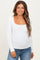woman wearing a white long sleeve maternity top with a square neckline and a baby bump visible