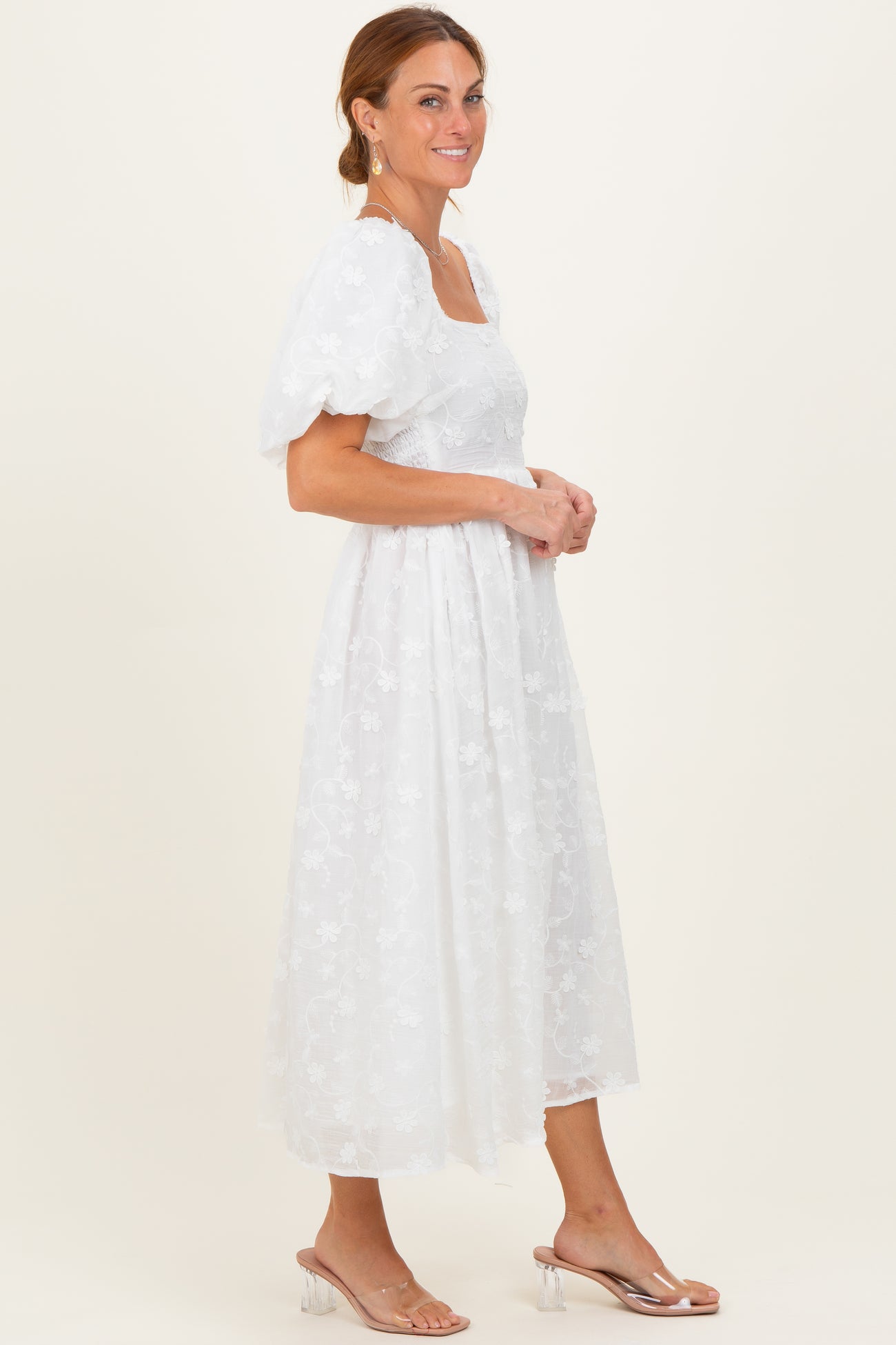 woman wearing a white floral embroidered midi dress with puff sleeves and a square neckline
