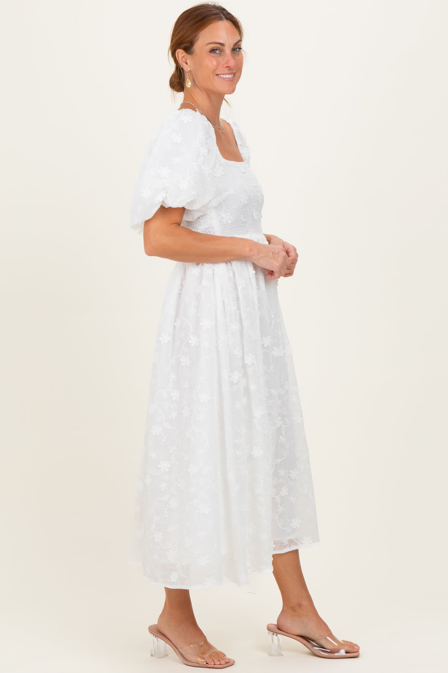 woman wearing a white floral embroidered midi dress with puff sleeves and a square neckline