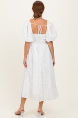 woman wearing a white puff sleeve midi dress with a smocked back and floral embroidery