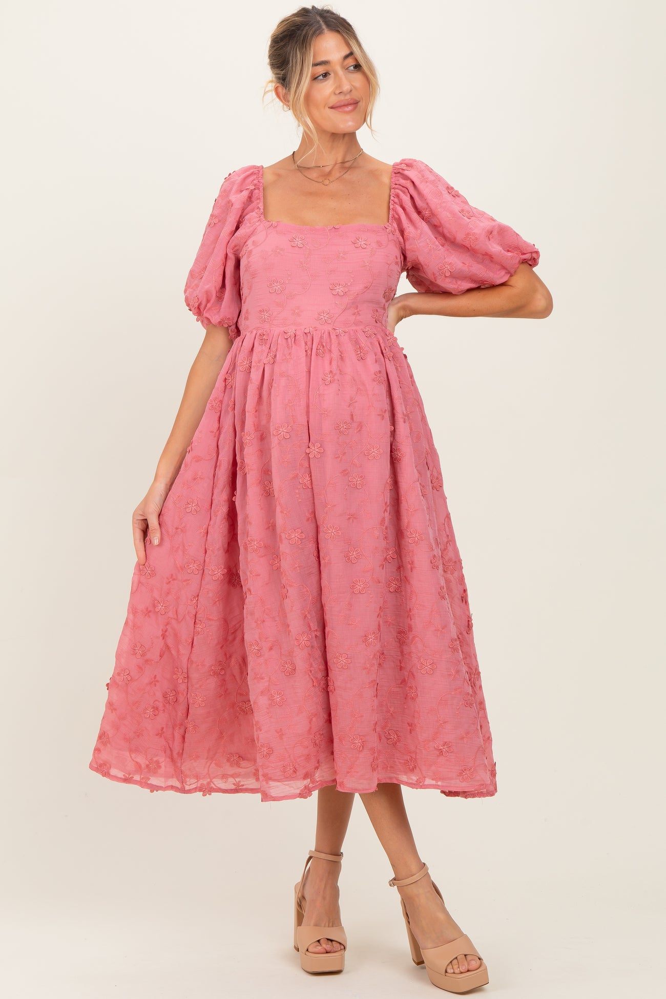 woman wearing a pink floral embroidered maternity dress with puff sleeves and a square neckline