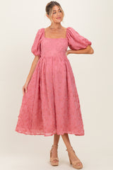 woman wearing a pink floral embroidered maternity dress with puff sleeves and a square neckline