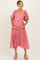 woman wearing a pink puff sleeve maternity dress with floral details and holding her baby bump