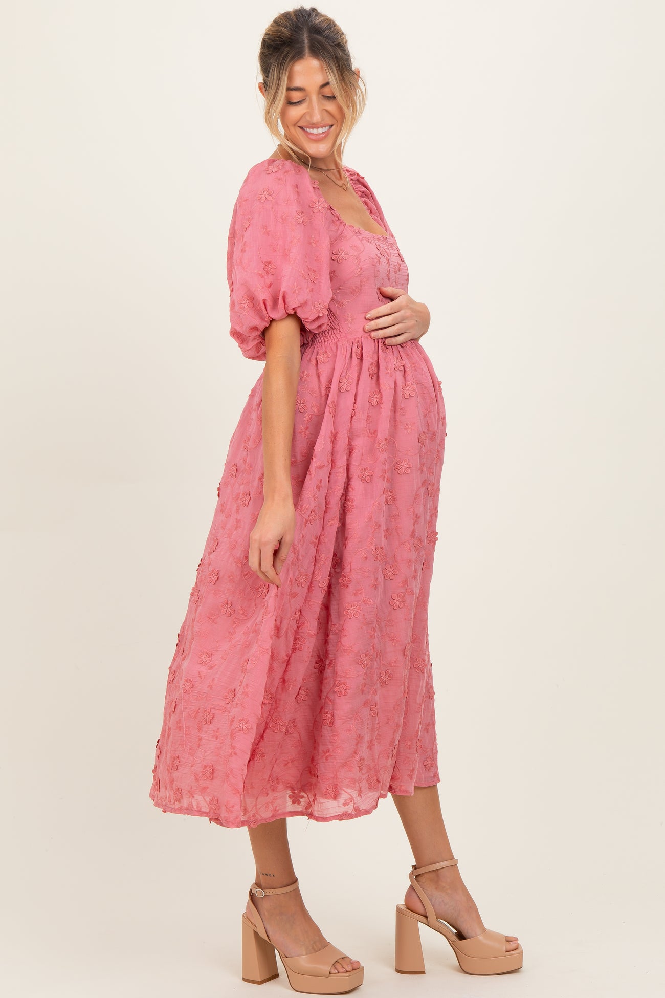 woman wearing a pink floral maternity dress with a cinched waist and puff sleeves, showing off her baby bump