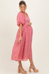 woman wearing a pink floral maternity dress with a cinched waist and puff sleeves, showing off her baby bump
