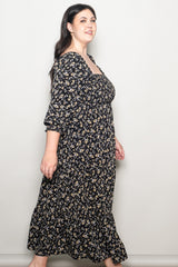woman wearing a black floral plus-size maxi dress with a square neckline and ruffled hem