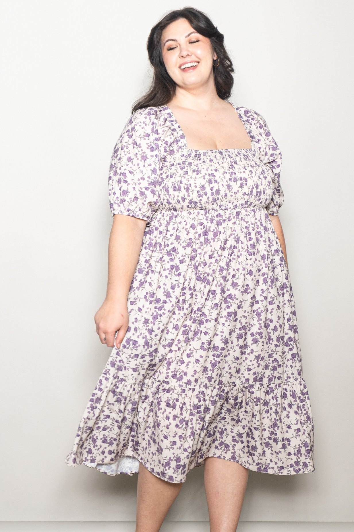 woman wearing a purple floral plus size dress with a square neckline and puff sleeves