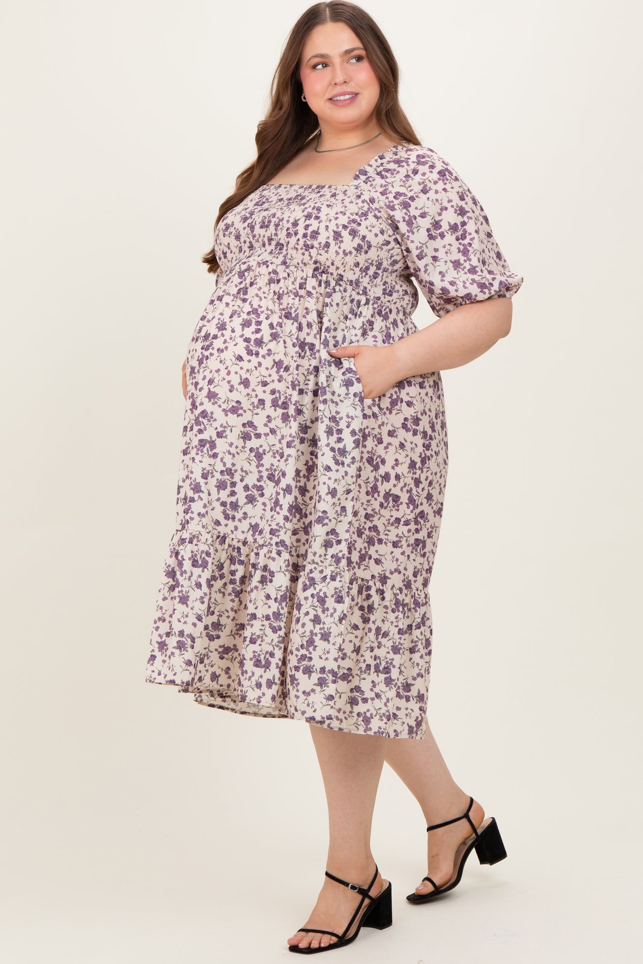 woman wearing a floral print maternity plus dress with short sleeves and pockets, showing her baby bump