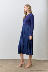 woman wearing a navy blue pleated midi dress with a fitted top and long sleeves