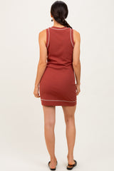 woman wearing a rust-colored sleeveless dress with contrasting stitching details and side slits