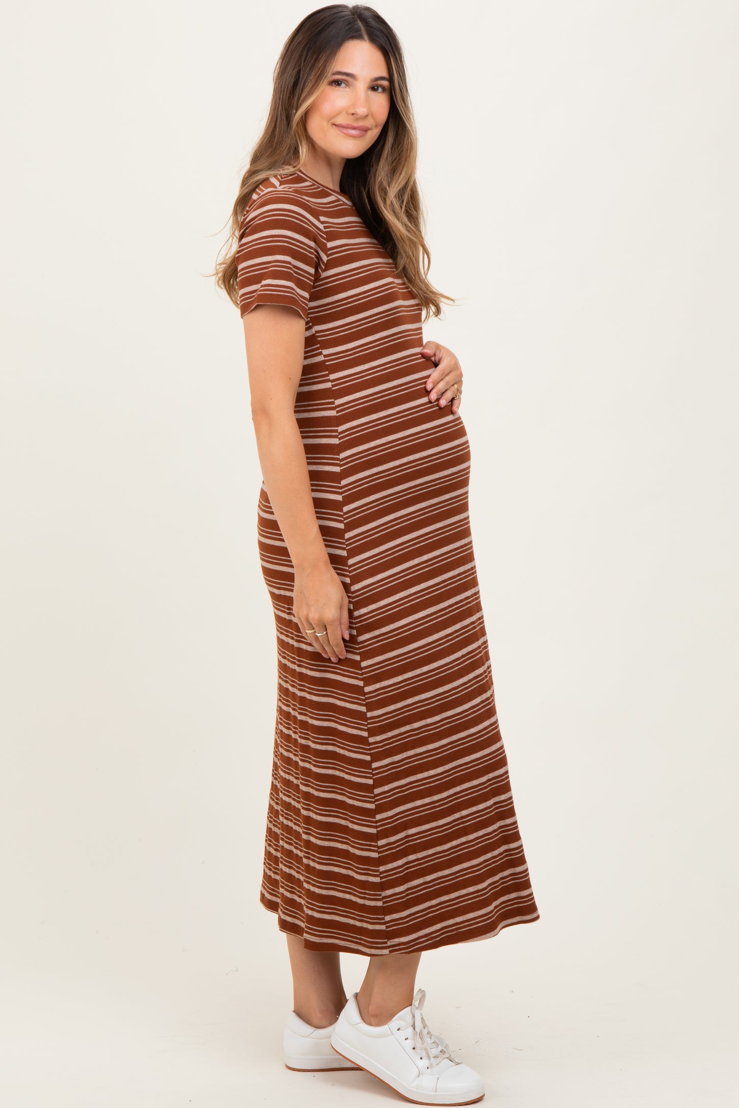 woman wearing a brown striped maternity dress and holding her baby bump