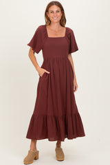 woman wearing a burgundy square neck maxi dress with short sleeves and a ruffled hem, featuring side pockets