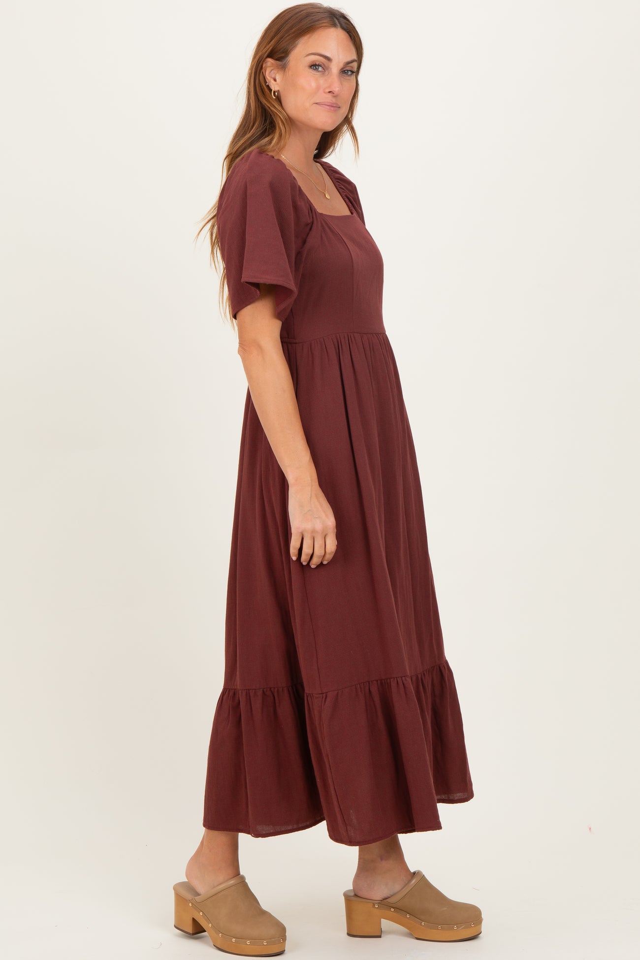 woman wearing a burgundy short sleeve maxi dress with a square neck and tiered ruffle hemline