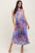 woman wearing a purple and blue tie-dye halter neck midi dress with a drawstring waist and pleated details
