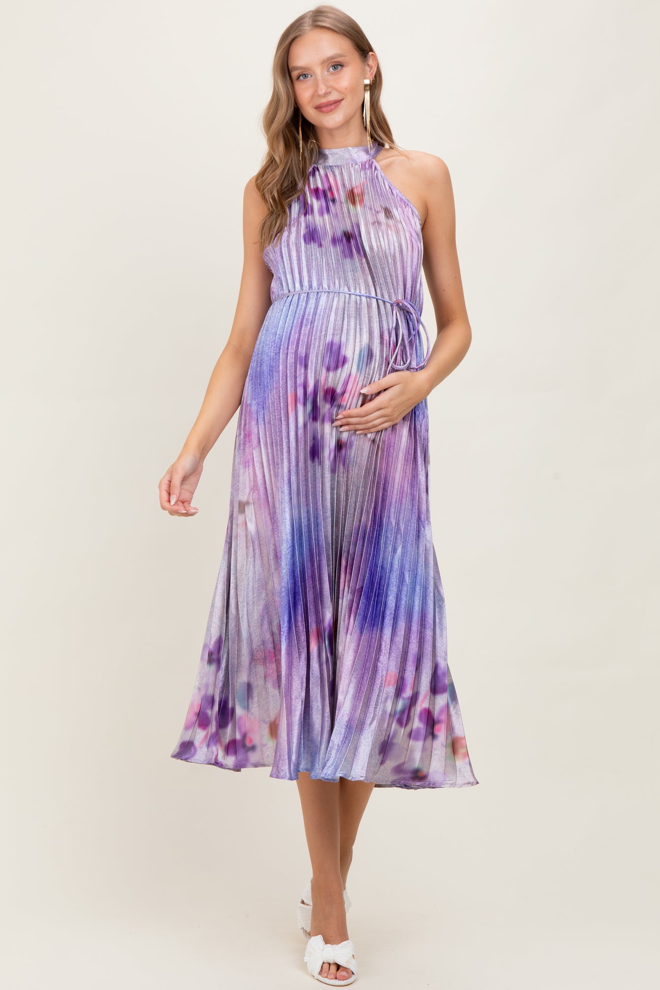 woman wearing a purple and blue halter neck pleated maternity dress with a flowing skirt and baby bump visible
