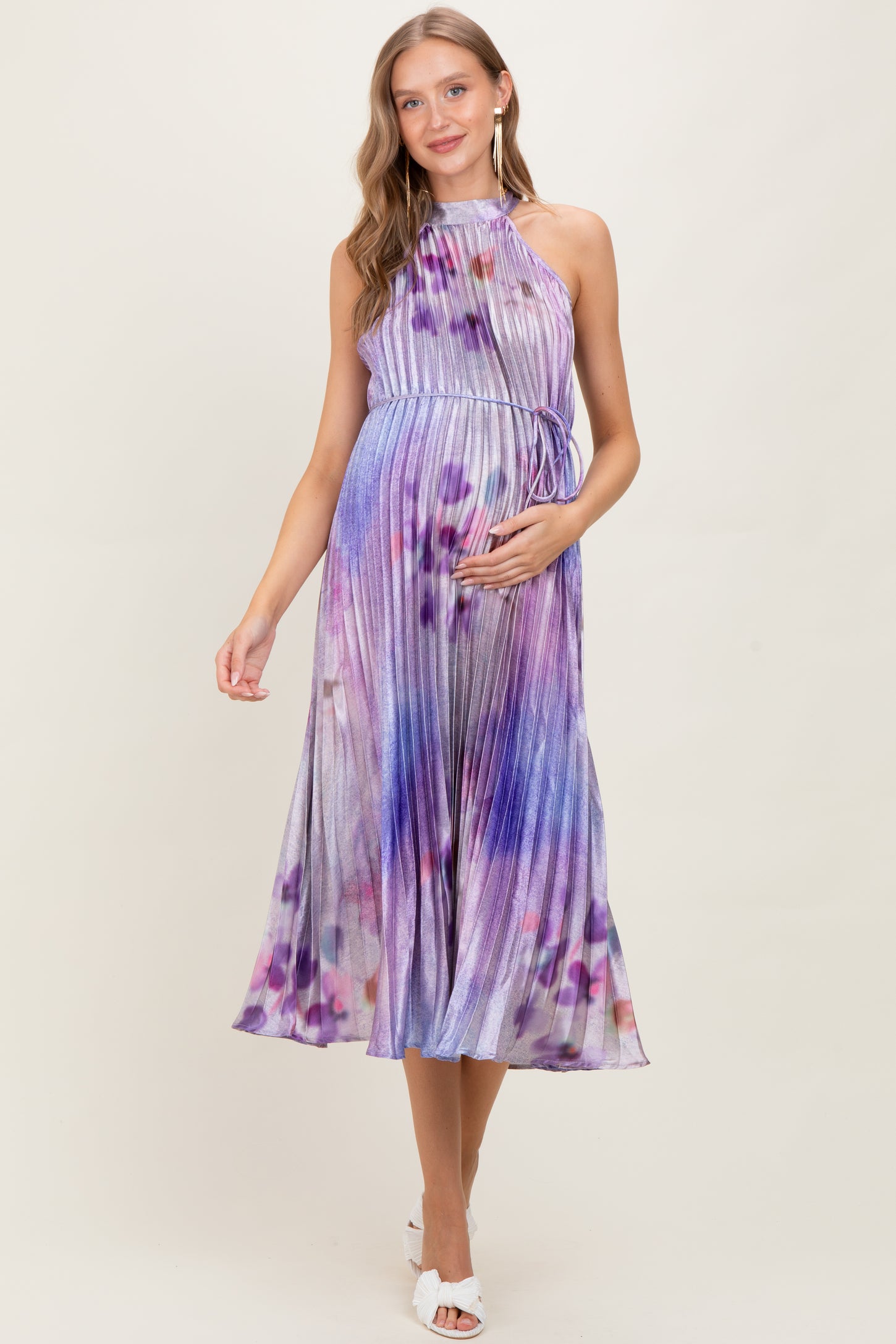 woman wearing a purple and blue halter neck pleated maternity dress with a flowing skirt and baby bump visible