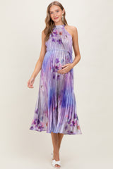 woman wearing a purple and blue halter neck pleated maternity dress with a flowing skirt and baby bump visible