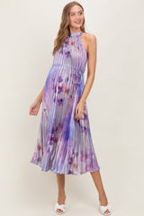 woman wearing a purple floral pleated maternity dress with a waist tie and a visible baby bump