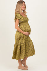 woman wearing a green polka dot maternity dress with ruffled sleeves and a baby bump