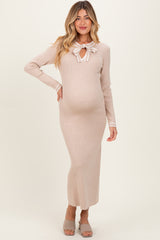 woman wearing a beige long sleeve maternity dress with a bow tie detail and a visible baby bump