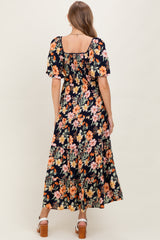 woman wearing a floral print maternity maxi dress with short puff sleeves and a square neckline, showing her baby bump