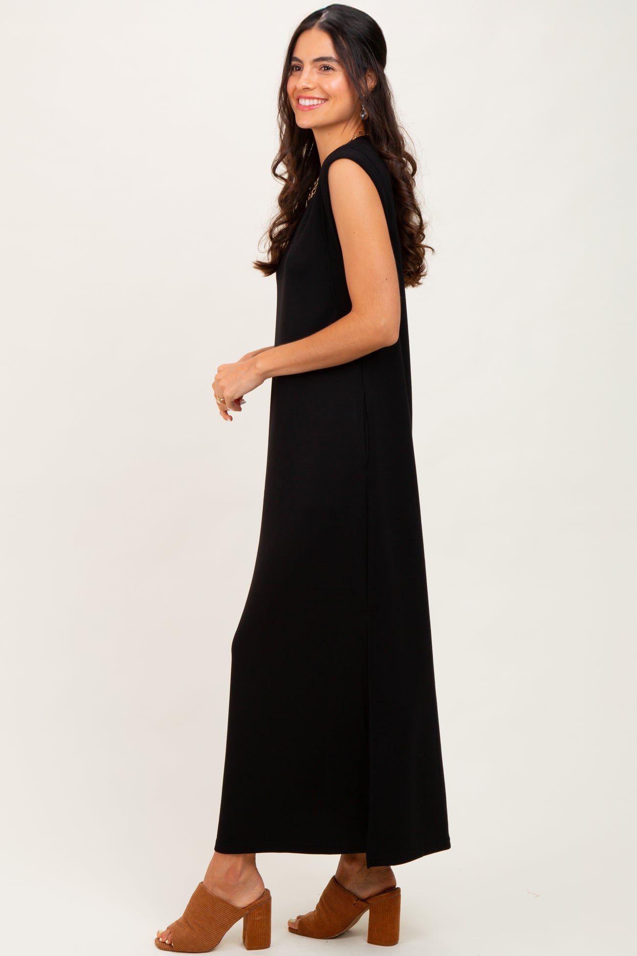 woman wearing a black sleeveless maxi dress with side slit and wearing brown heeled sandals
