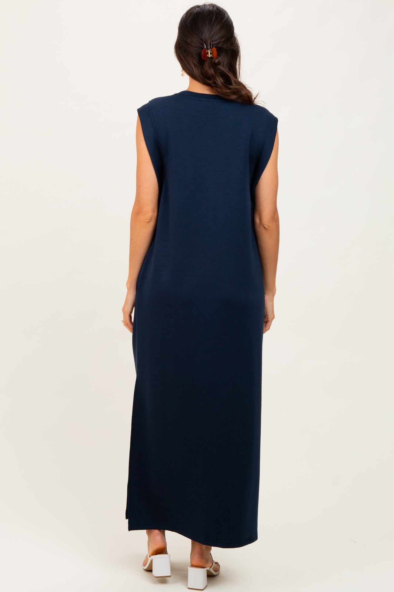 woman wearing a navy blue sleeveless maxi dress, view from the back showing a long silhouette and side slits