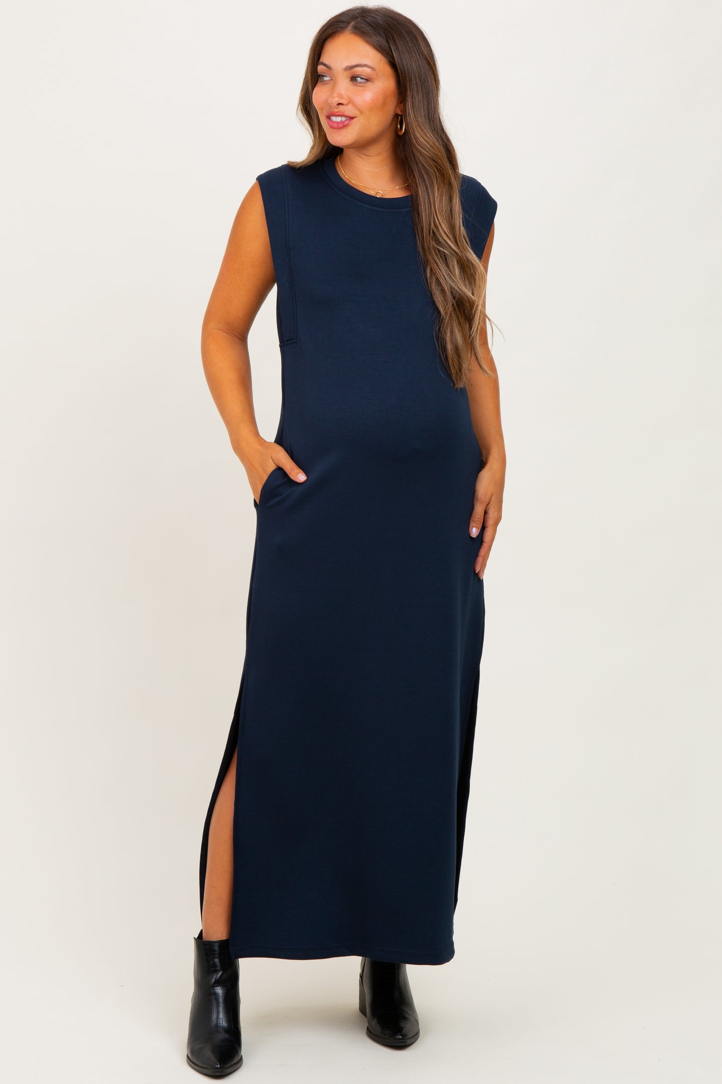 woman wearing a navy blue sleeveless maternity maxi dress with side pockets and high slits