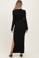 woman wearing a black long sleeve maternity dress with a side slit, viewed from the back