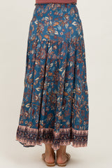 woman wearing a flowy blue floral maxi skirt with an elastic waistband and tiered design, viewed from the back