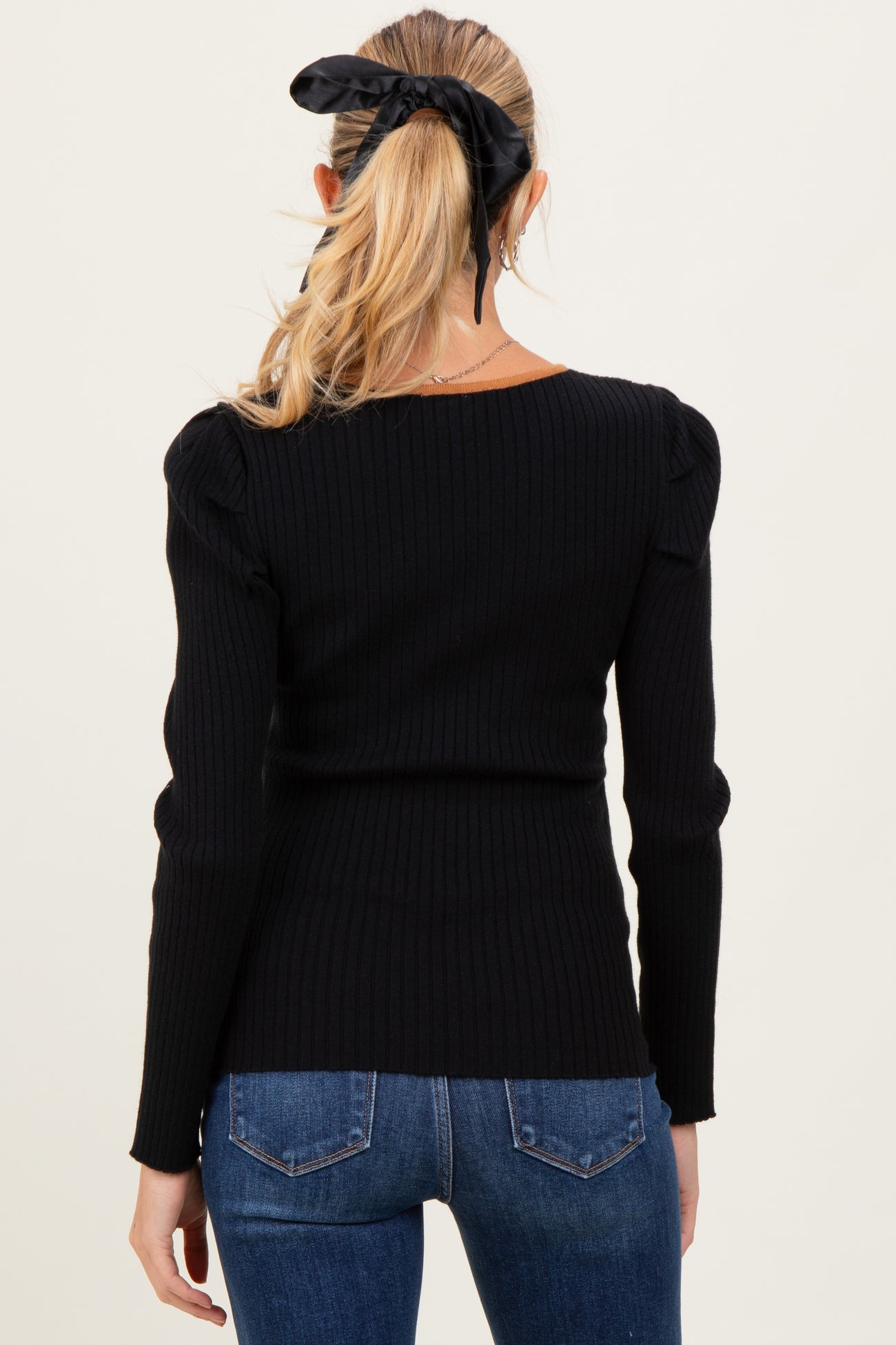 woman wearing a black ribbed maternity top with puff sleeves, seen from the back
