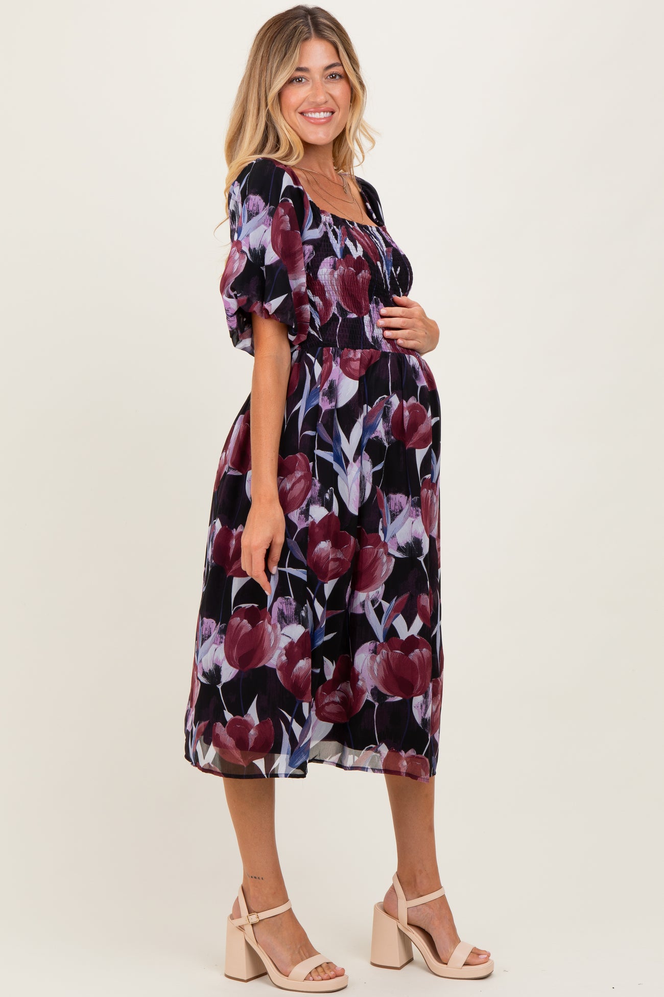 woman wearing a black floral maternity dress with puff sleeves and a visible baby bump