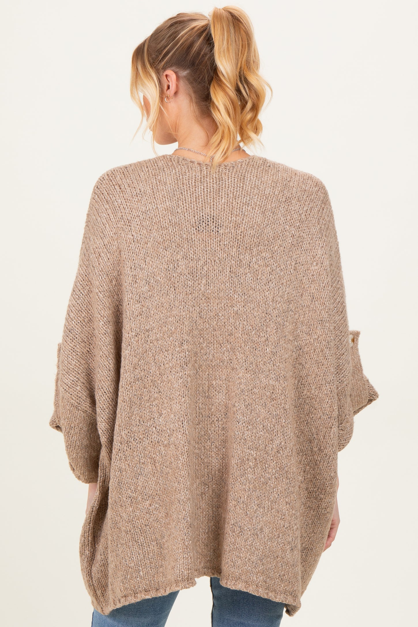woman wearing a cozy oversized beige maternity sweater with batwing sleeves, viewed from the back