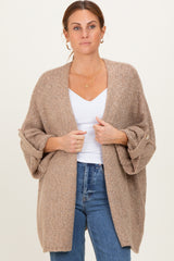 woman wearing a beige oversized cardigan with rolled sleeves, styled over a white top and jeans
