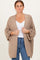 woman wearing a beige oversized cardigan with rolled sleeves, styled over a white top and jeans