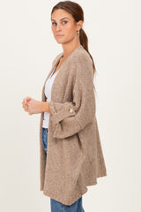 woman wearing a beige open cardigan with three-quarter sleeves and a relaxed fit, styled with a white top and blue jeans