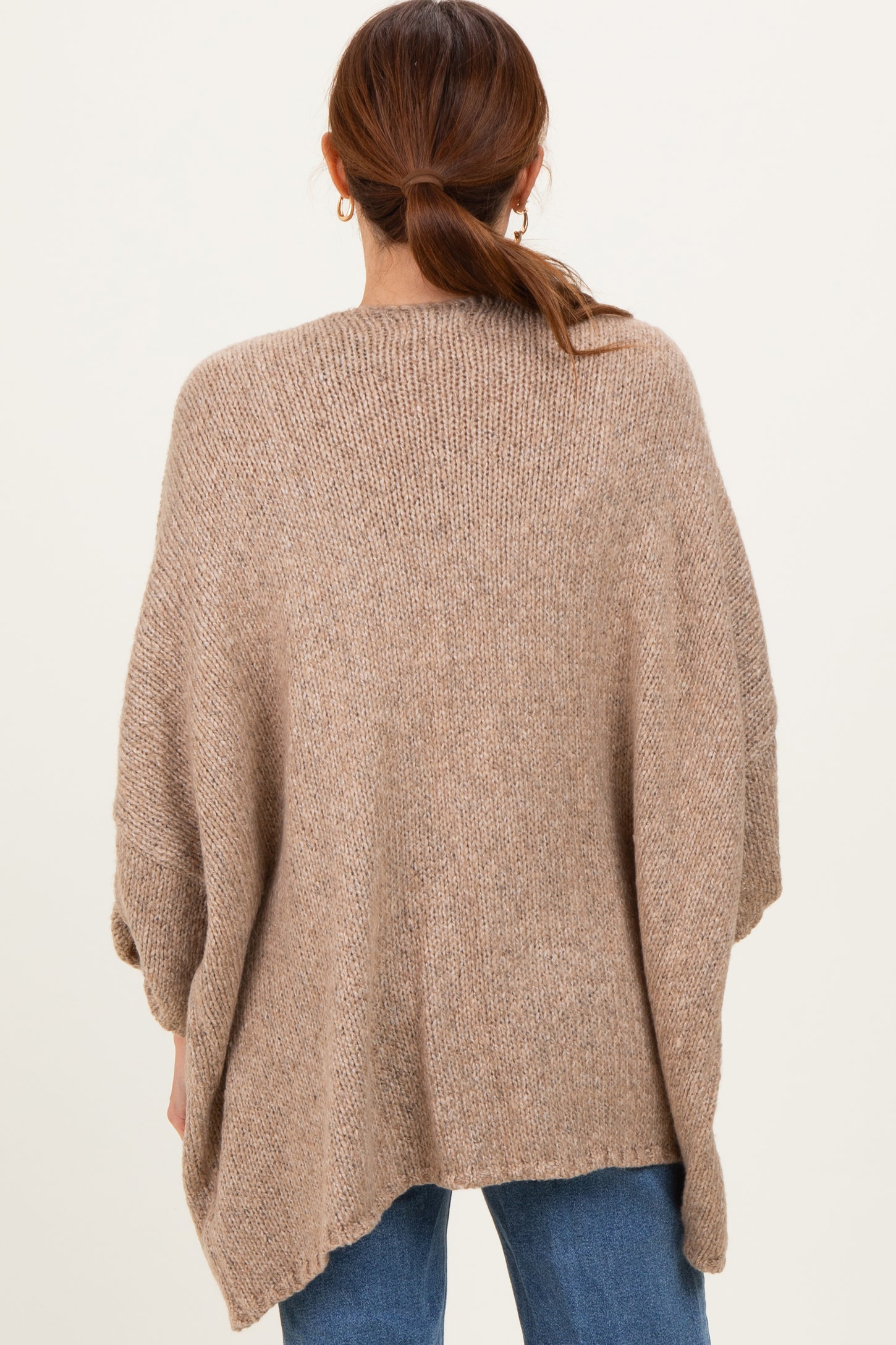 woman wearing a oversized brown knitted poncho sweater with a loose fit and rolled sleeves