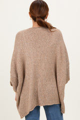 woman wearing a oversized brown knitted poncho sweater with a loose fit and rolled sleeves