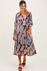 woman wearing a multicolored floral print maternity dress with three-quarter sleeves and a baby bump visible