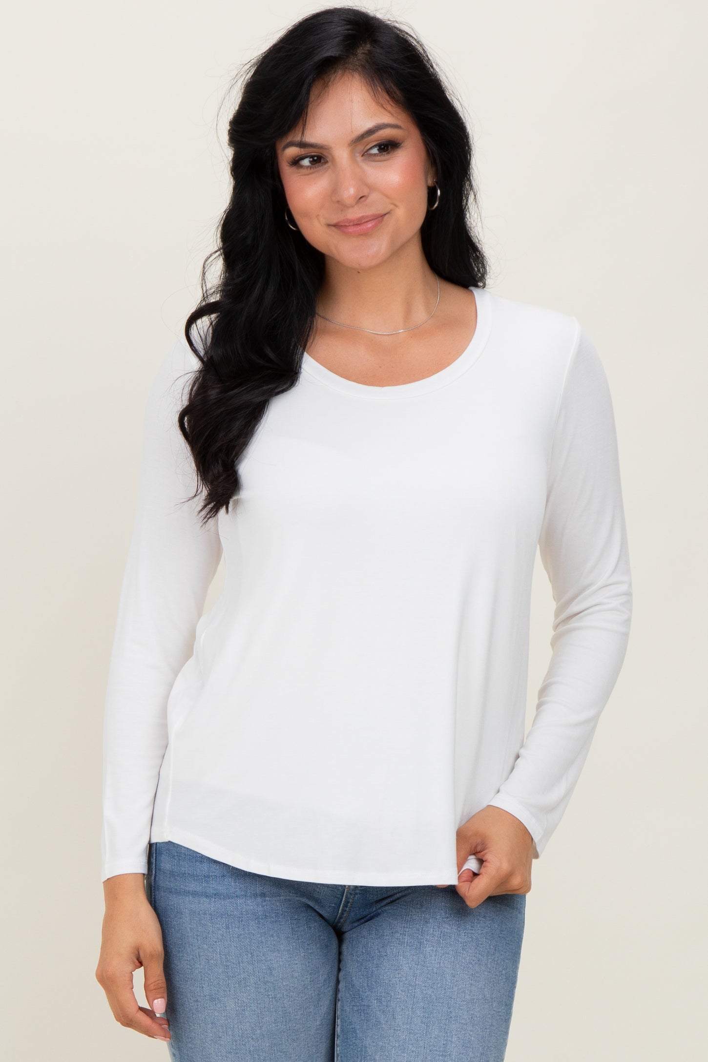 woman wearing a white long sleeve top with a round neckline and paired with blue jeans