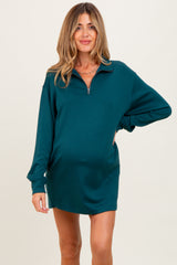 woman wearing a teal maternity zip-up dress with a relaxed fit and long sleeves, showing her baby bump