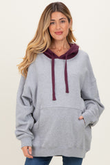 woman wearing a gray oversized maternity hoodie with a burgundy hood and front pocket