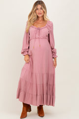 woman wearing a dusty pink maternity maxi dress with long sleeves and tiered ruffles, showing a baby bump