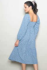 woman wearing a light blue midi dress with black polka dots and puff sleeves, shown from the back