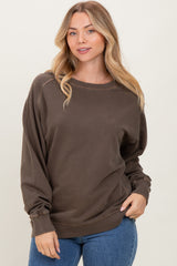 woman wearing a dark brown oversized long sleeve sweatshirt with ribbed cuffs and a relaxed fit