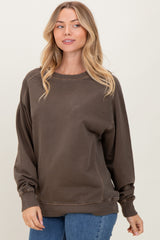 woman wearing a brown sweatshirt with a relaxed fit and long sleeves, styled with blue jeans