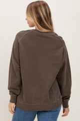 woman wearing a brown oversized sweatshirt with a crew neckline and ribbed cuffs, viewed from the back